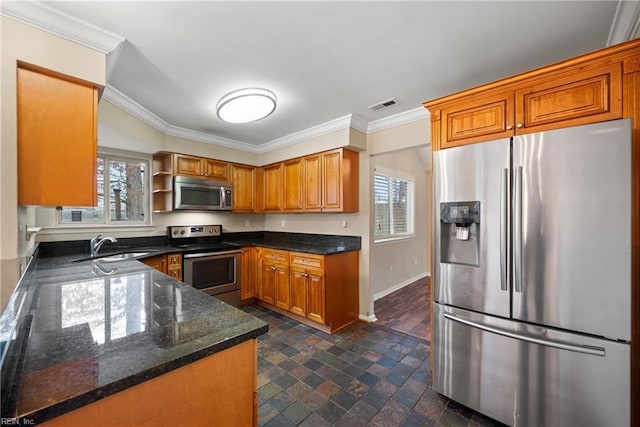 kitchen with stainless steel appliances, a sink, visible vents, dark stone countertops, and crown molding