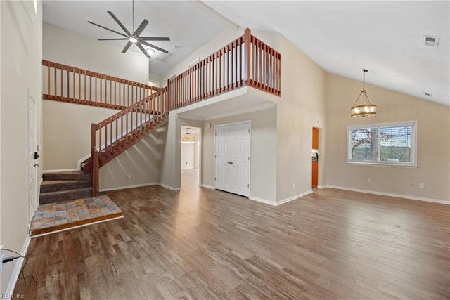 unfurnished living room featuring ceiling fan with notable chandelier, stairway, wood finished floors, and visible vents