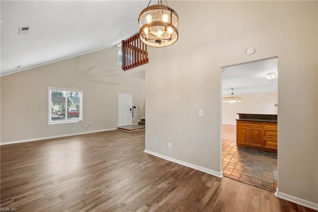 unfurnished living room featuring baseboards, visible vents, dark wood-type flooring, and a notable chandelier