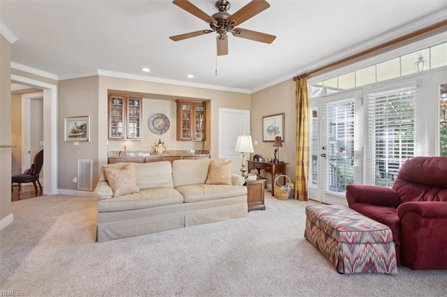 living area with visible vents, light colored carpet, ceiling fan, wet bar, and crown molding