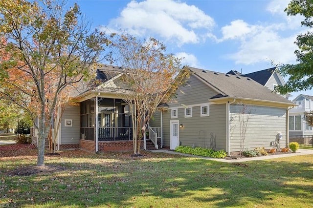 rear view of property featuring a sunroom and a lawn