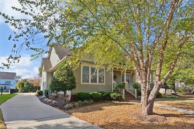 view of property hidden behind natural elements with driveway and fence