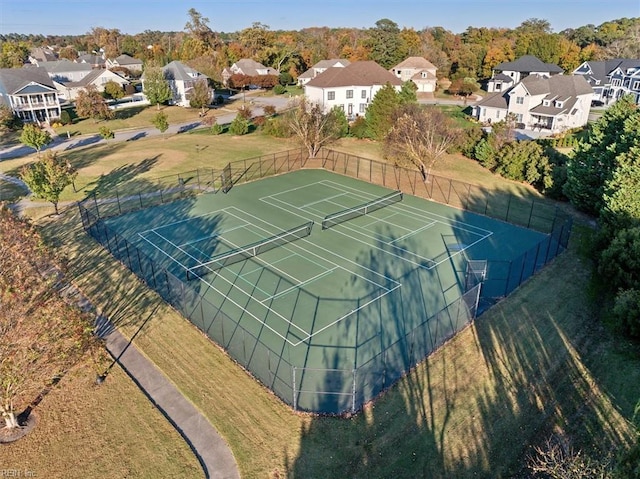 view of tennis court featuring fence and a residential view