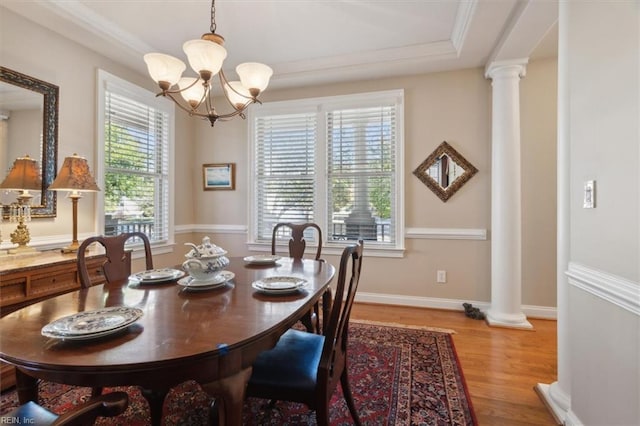 dining space with baseboards, light wood-style flooring, crown molding, ornate columns, and a notable chandelier