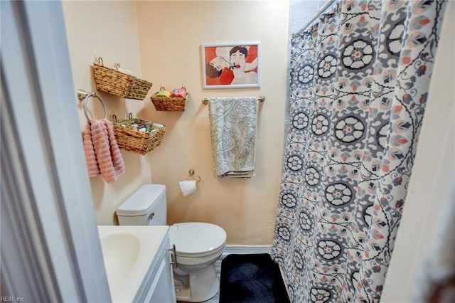 bathroom featuring toilet, a shower with curtain, baseboards, and vanity