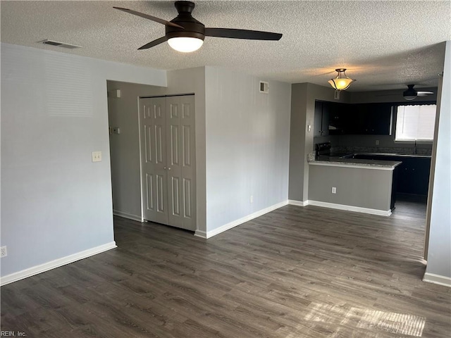 kitchen featuring a sink, visible vents, baseboards, light countertops, and dark wood finished floors