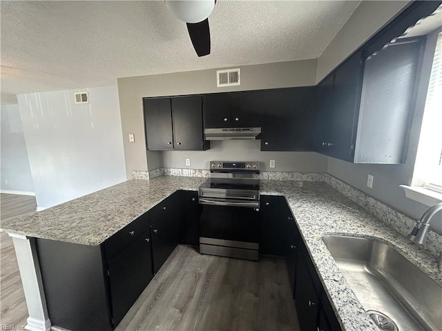 kitchen with visible vents, a sink, a peninsula, under cabinet range hood, and stainless steel electric range