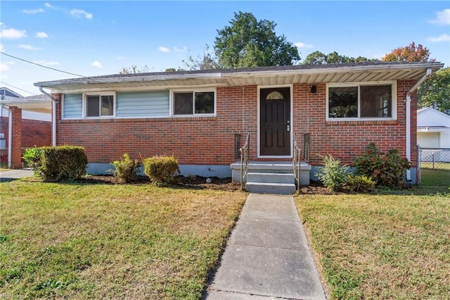 view of front facade featuring a front yard, brick siding, and fence