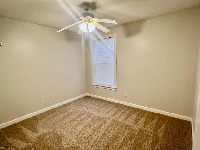 empty room with baseboards, dark carpet, and a ceiling fan