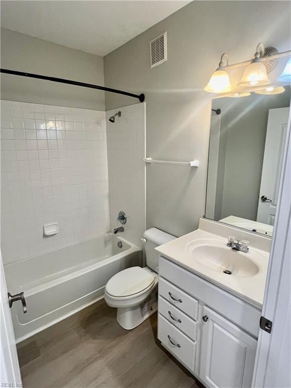 full bathroom with visible vents, toilet, vanity, wood finished floors, and  shower combination