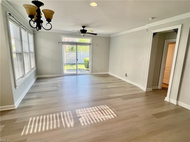 unfurnished room with ceiling fan with notable chandelier, baseboards, crown molding, and wood finished floors