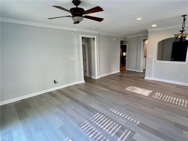 unfurnished living room featuring a ceiling fan, crown molding, baseboards, and wood finished floors