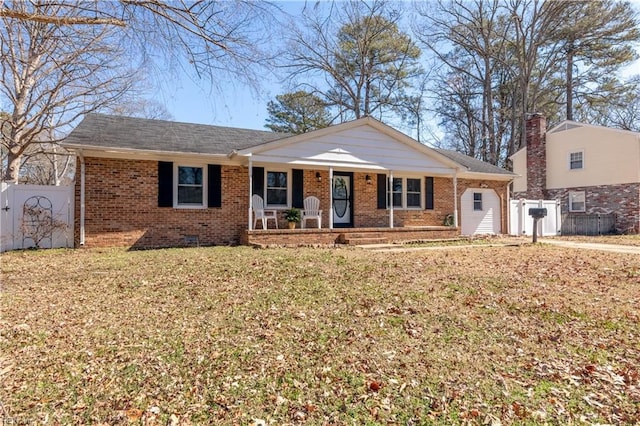 single story home with a porch, a front yard, brick siding, and fence