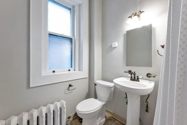 half bathroom featuring a sink, toilet, and radiator heating unit