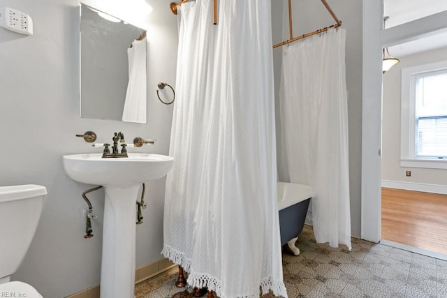 bathroom featuring granite finish floor, toilet, and baseboards