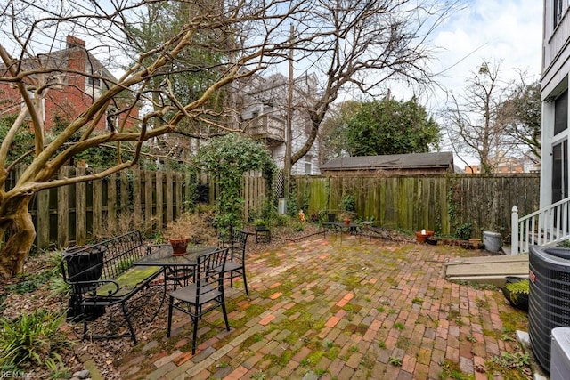 view of yard featuring a patio, outdoor dining area, cooling unit, and a fenced backyard