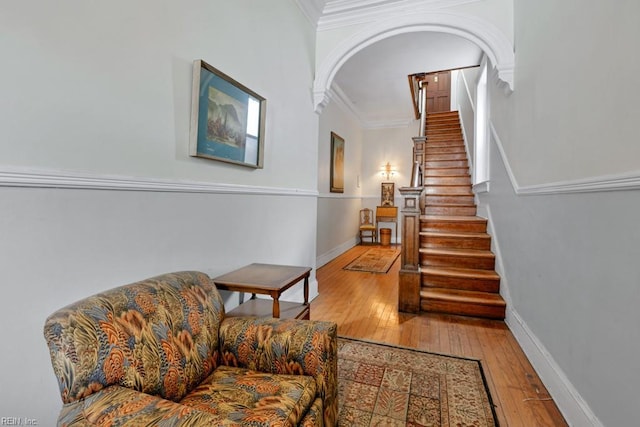 interior space with arched walkways, baseboards, crown molding, and hardwood / wood-style floors