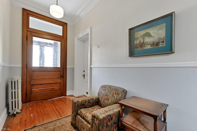 entryway with radiator, ornamental molding, and wood finished floors