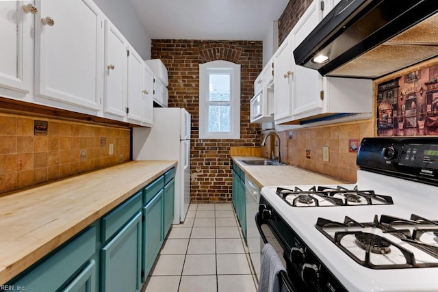 kitchen with gas range oven, white cabinets, a sink, brick wall, and under cabinet range hood