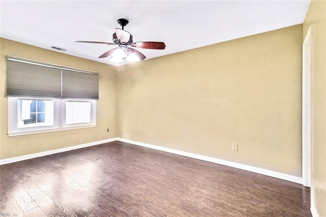 spare room with dark wood-type flooring, visible vents, and baseboards