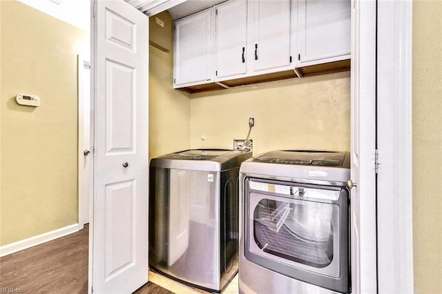 washroom with cabinet space, baseboards, washer and clothes dryer, and wood finished floors