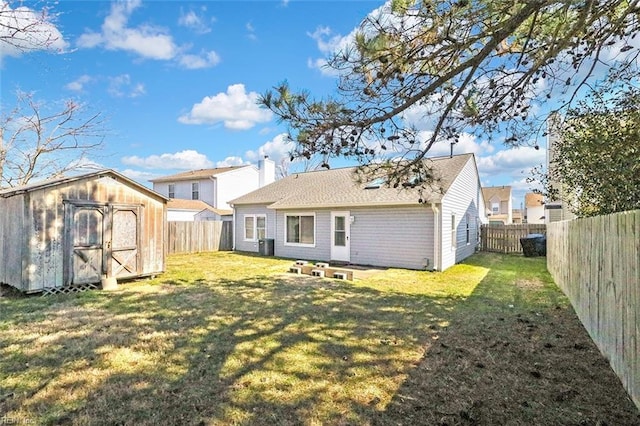 back of property featuring a storage shed, a fenced backyard, a lawn, and an outbuilding