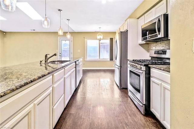 kitchen featuring stone counters, dark wood-type flooring, a sink, appliances with stainless steel finishes, and pendant lighting