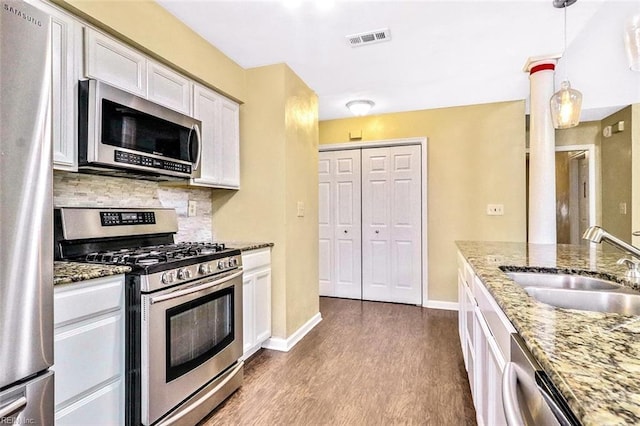 kitchen with stainless steel appliances, dark wood-type flooring, a sink, visible vents, and backsplash