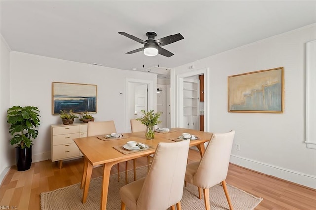 dining room featuring light wood-style flooring, baseboards, ceiling fan, and crown molding