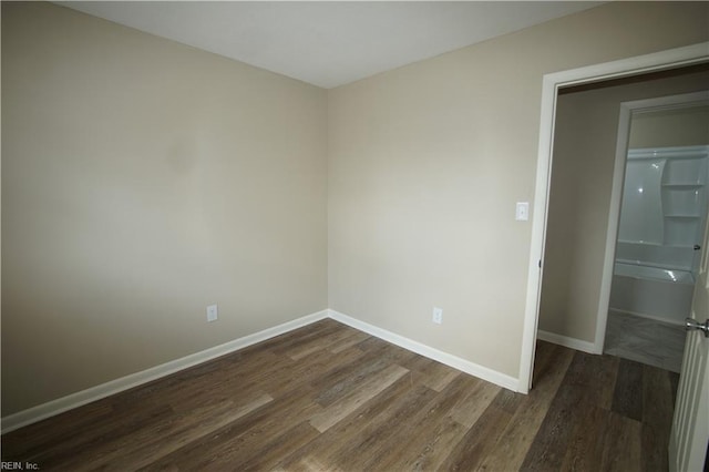 unfurnished room featuring dark wood-type flooring and baseboards