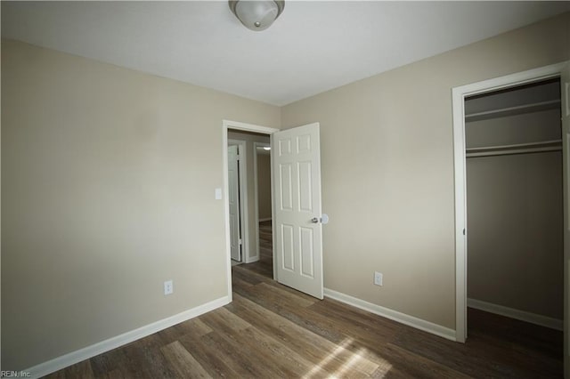 unfurnished bedroom with a closet, wood finished floors, and baseboards