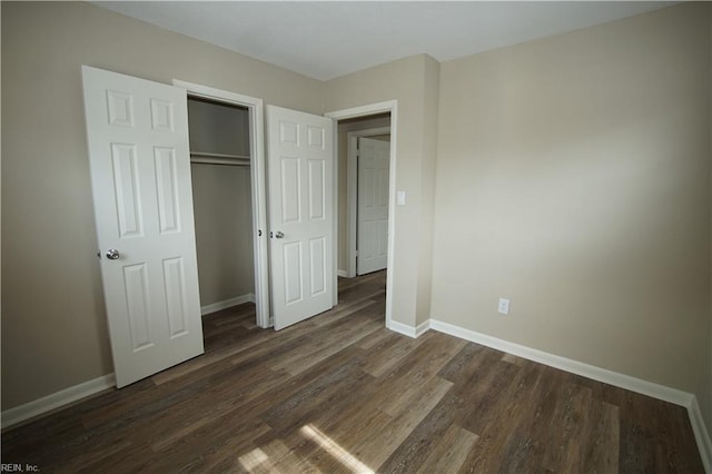 unfurnished bedroom featuring dark wood-type flooring, a closet, and baseboards