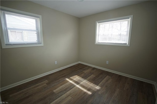 empty room with baseboards and dark wood finished floors