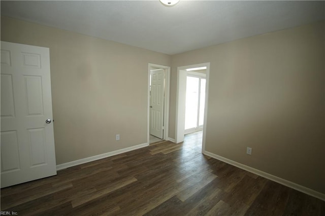 empty room featuring dark wood-style floors and baseboards