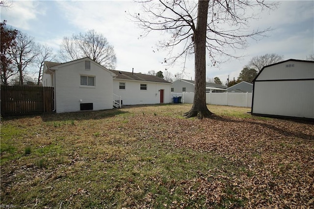 rear view of property featuring an outbuilding, a fenced backyard, a lawn, and a shed