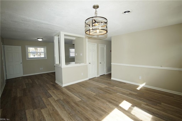 empty room featuring baseboards, visible vents, a chandelier, and wood finished floors