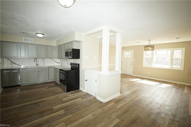 kitchen featuring a sink, visible vents, appliances with stainless steel finishes, gray cabinets, and dark wood finished floors