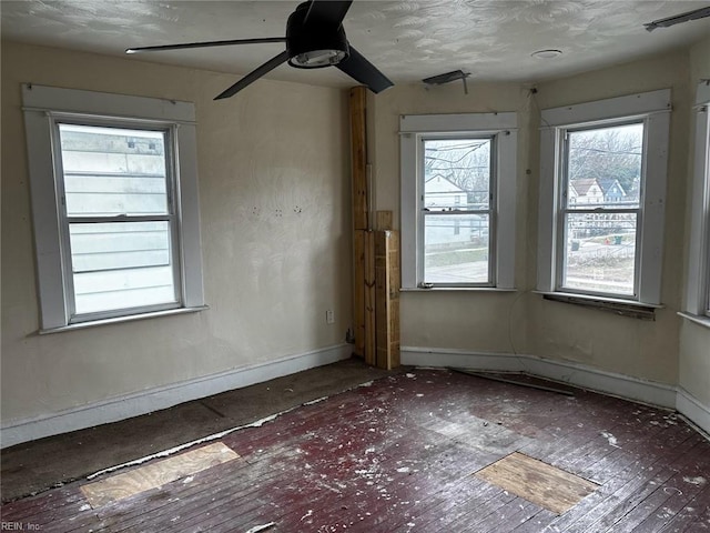 unfurnished room featuring a healthy amount of sunlight, visible vents, baseboards, and a ceiling fan