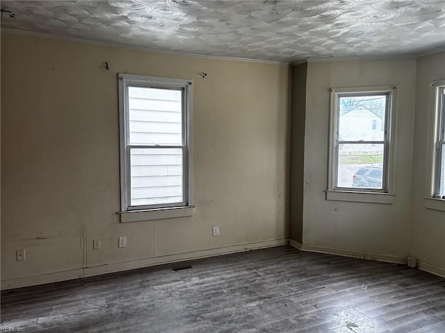 unfurnished room featuring ornamental molding, visible vents, baseboards, and wood finished floors