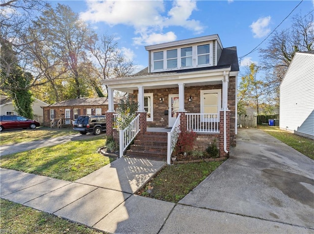 view of front of property with a porch, a front yard, and brick siding