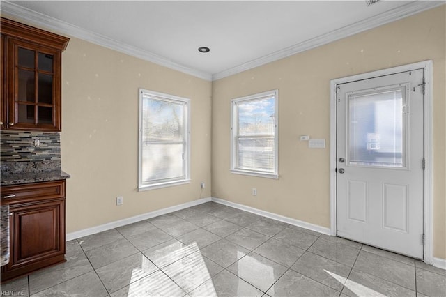 unfurnished dining area with light tile patterned floors, baseboards, and crown molding