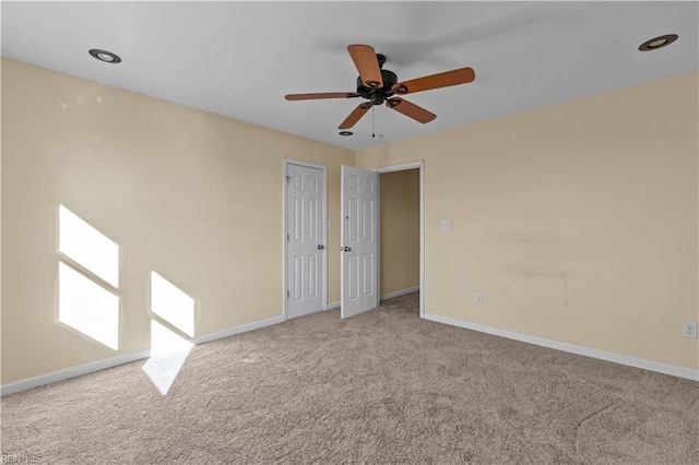 carpeted empty room featuring a ceiling fan and baseboards