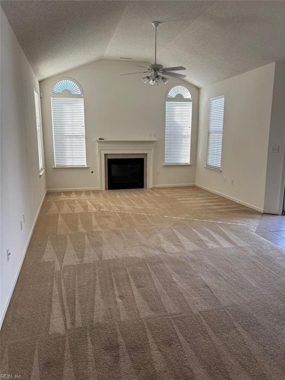 unfurnished living room with a ceiling fan, light colored carpet, lofted ceiling, a textured ceiling, and a fireplace