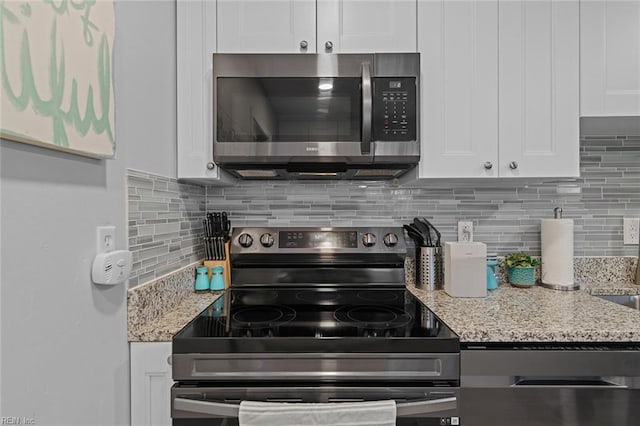 kitchen featuring decorative backsplash, stainless steel microwave, white cabinets, and electric stove