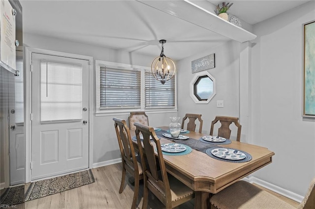 dining area featuring baseboards, a notable chandelier, and light wood finished floors