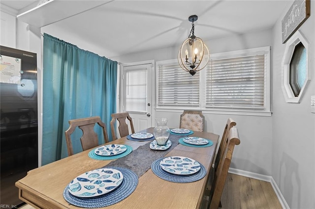 dining area featuring baseboards, a notable chandelier, and wood finished floors