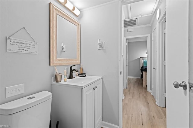 bathroom featuring baseboards, visible vents, toilet, wood finished floors, and vanity