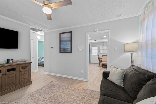 living room featuring ornamental molding, light wood-style flooring, a textured ceiling, and baseboards