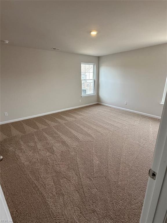 empty room with carpet, visible vents, and baseboards