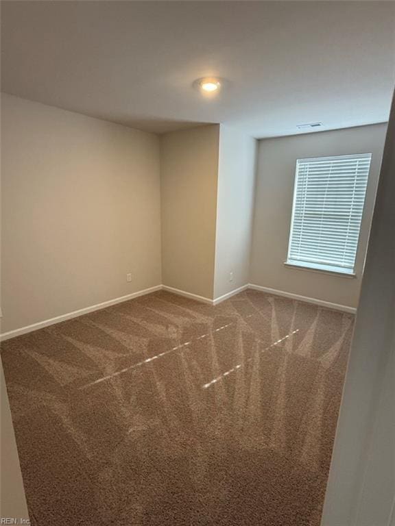 empty room with carpet floors, visible vents, and baseboards